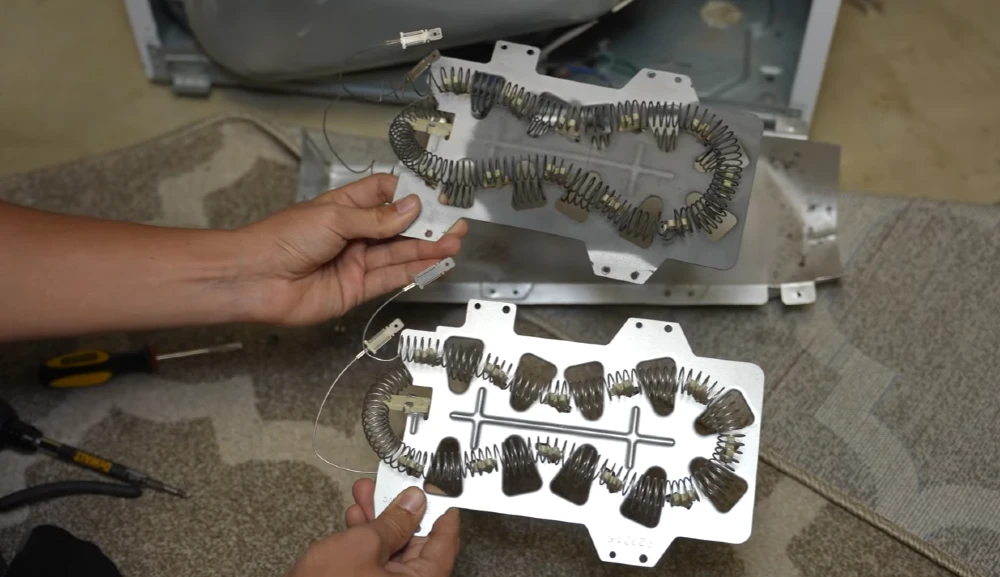 Hands holding dryer heating coils with tools nearby for heating element repair