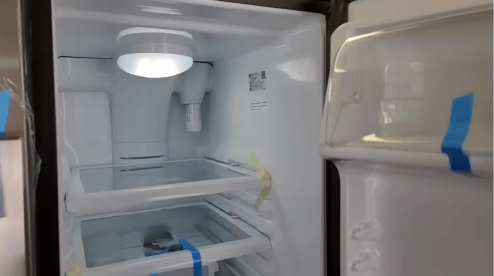 Open refrigerator with taped glass shelves prepared for transport or repair