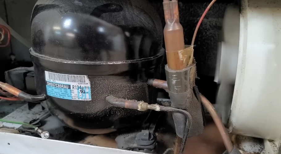 Refrigerator compressor close-up with copper tubing and R134a label