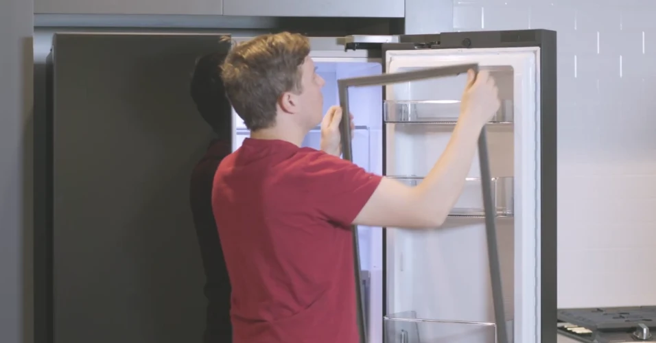 Pensacola refrigerator repair technician replacing a door gasket in a modern kitchen