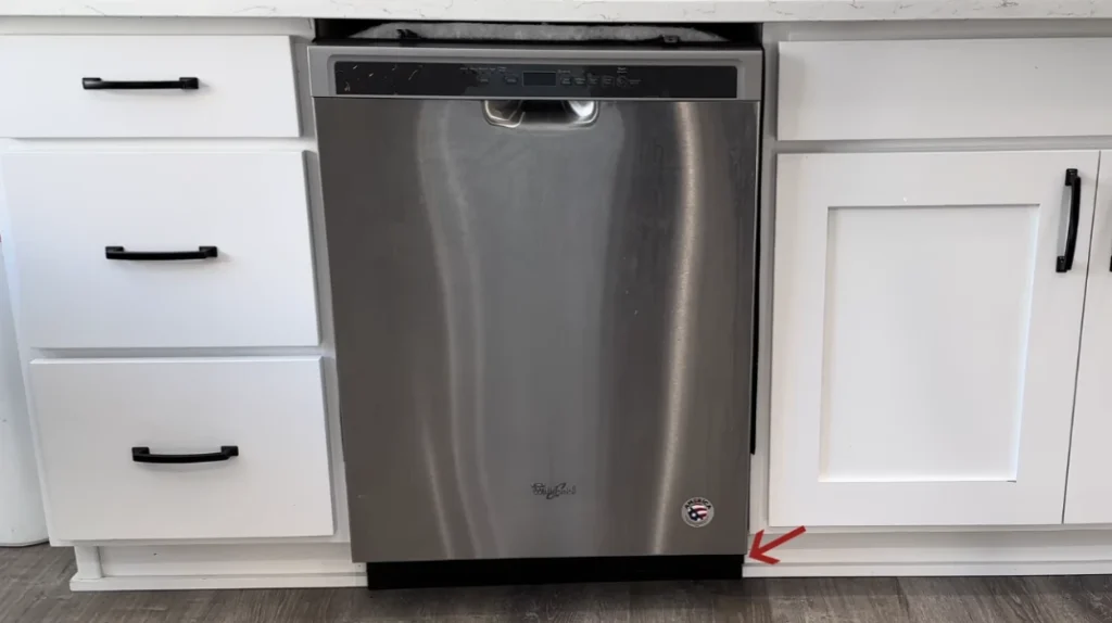 Stainless steel dishwasher between white cabinets with arrow pointing to lower right – Dishwasher Repair Pensacola.