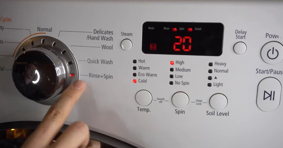 Hand pointing at washing machine control panel with cycle knob set to 20 minutes.