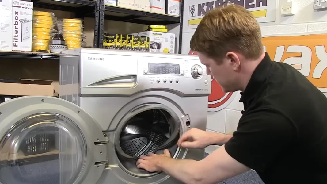 Person inspecting open drum of Samsung front-load washer in store.